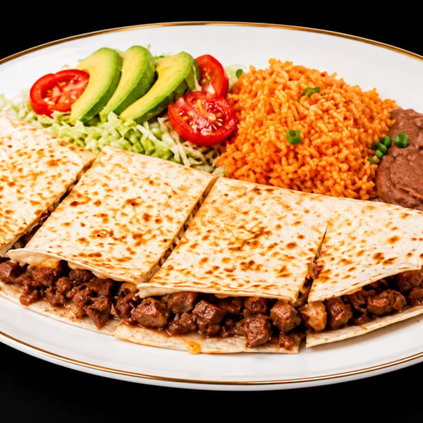 Beef quesadilla with rice, refried beans, shredded lettuce, avocado slices, and tomato on a white plate.